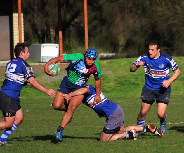 Hobart Harlequins centre Sid Fielea is tackled by Taroona Penguins’ Jeremy Climie as Mikey Whyte and Christo Le Grange look to turn over possession.