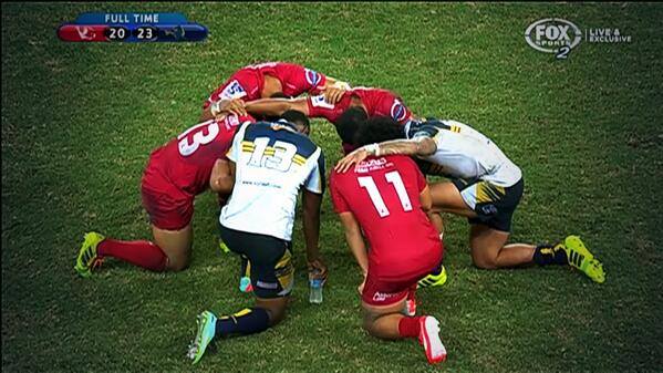 After the siren sounded, Pacific Islander players from Brumbies Rugby & Reds Rugby pray on centre of ground